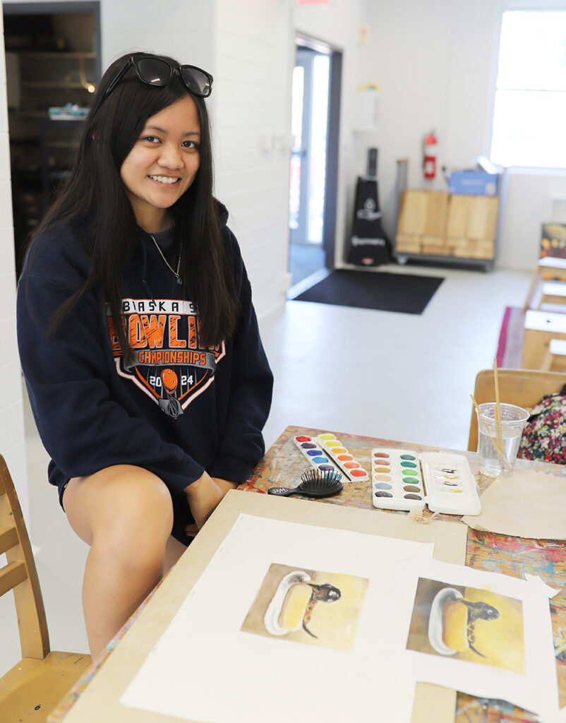 student displaying her watercolor paintng