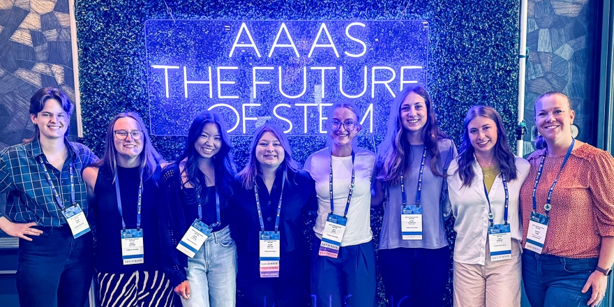 students standing in front of neon sign