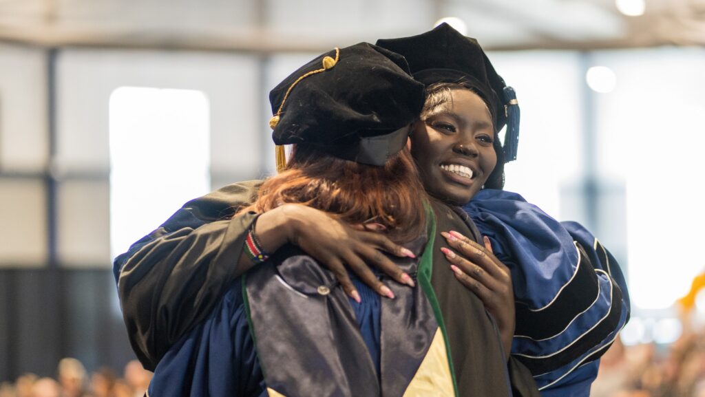 graduates hugging and smiling