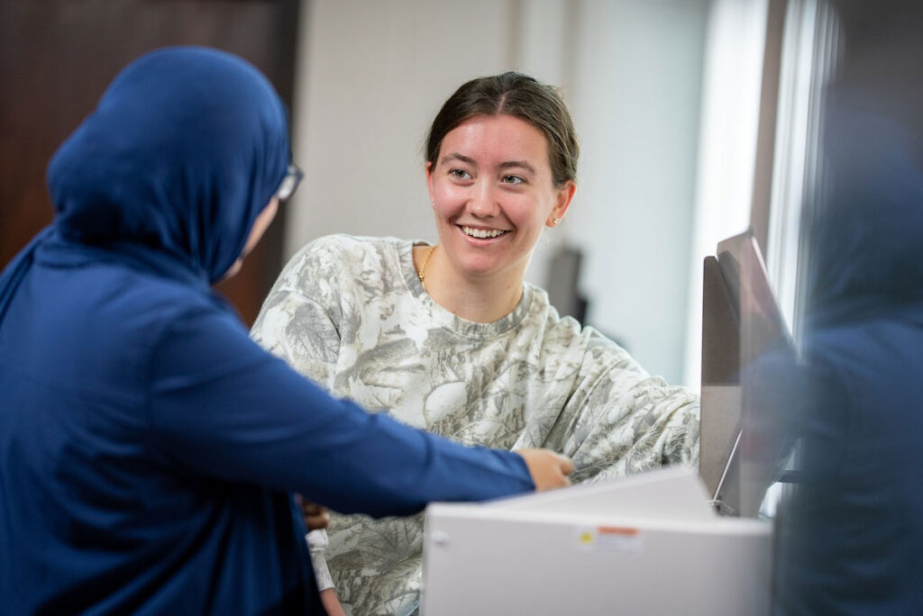 Student interacting with faculty member in chemistry lab.