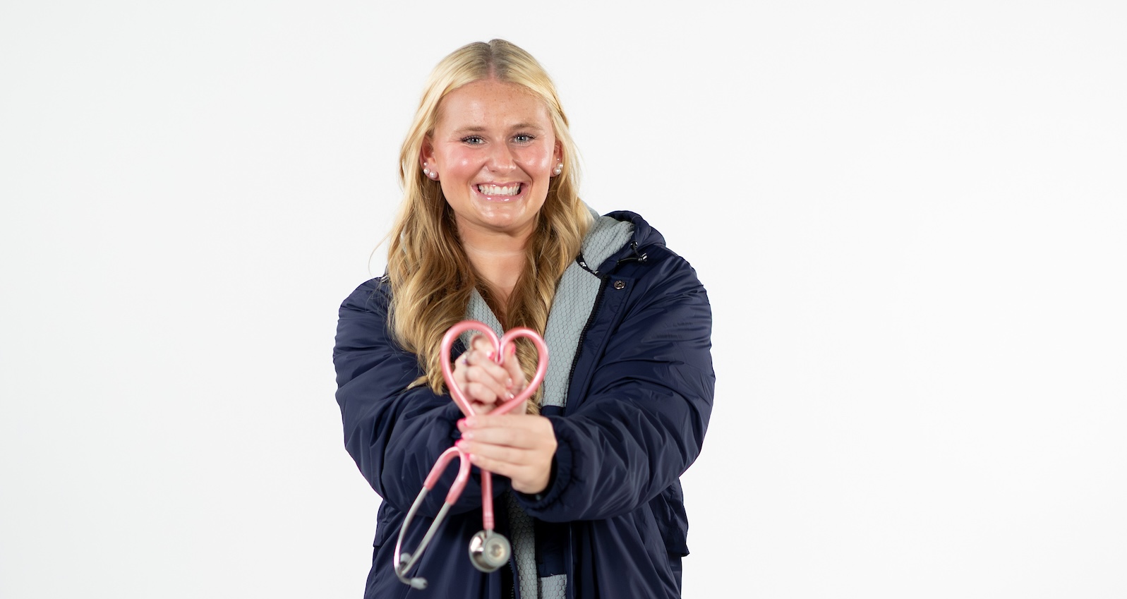 female swimmer holding a stethoscope, smiling at camera