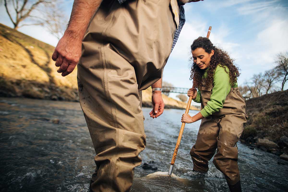 With an instructor in the forefront student holds net underwater to gather her findings for aquatic and environmental research.