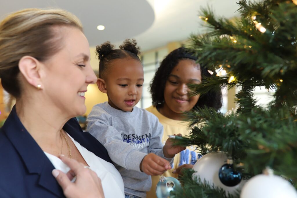 two women and a young child decorating a christmas tree