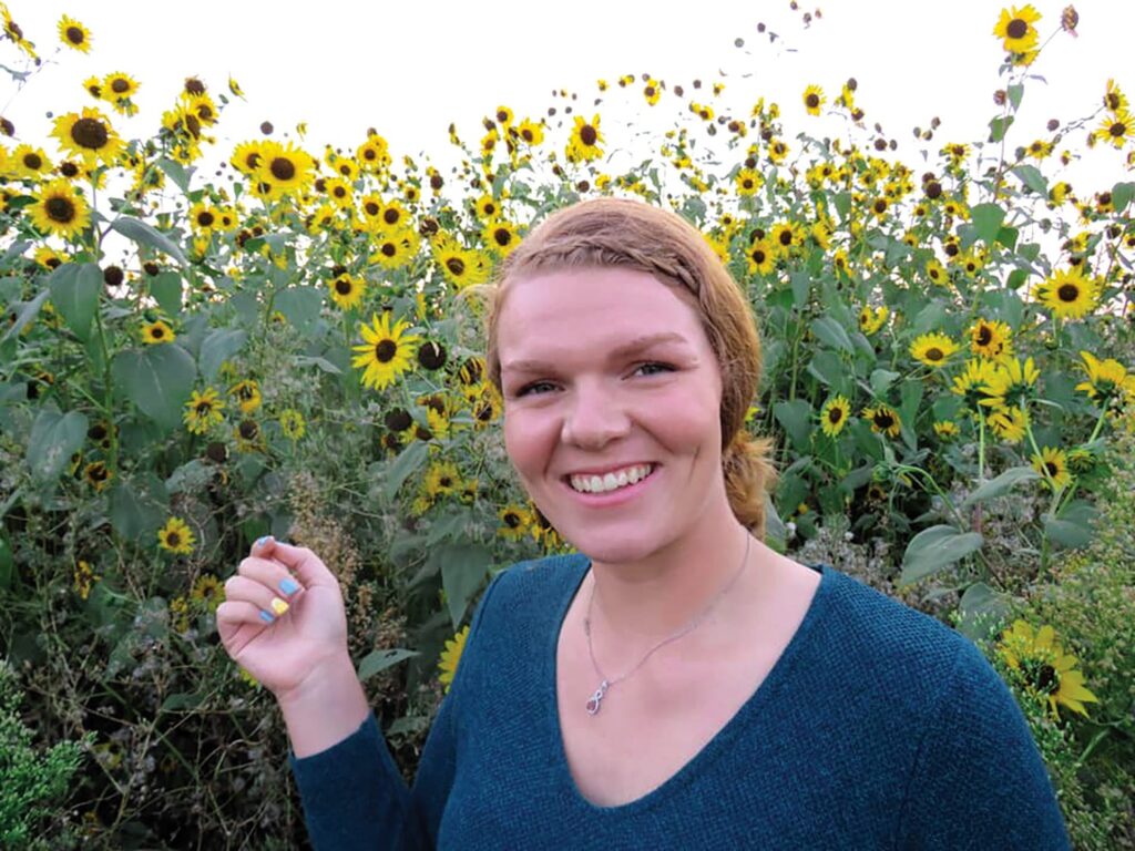 Student standing in front of wildflowers