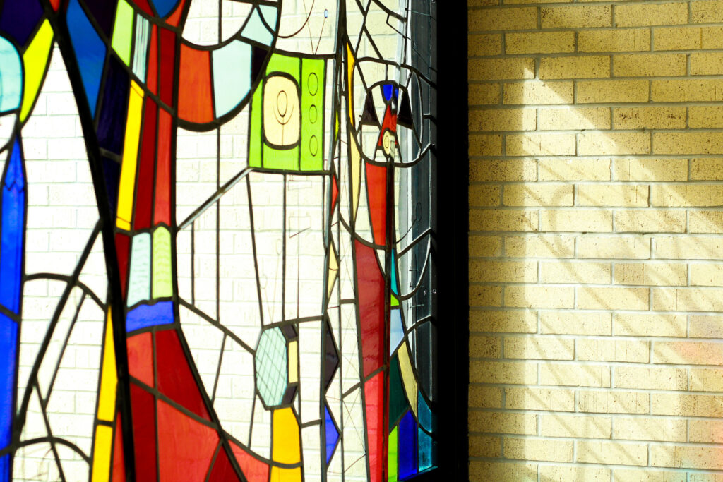 Abstract stained glass window with colorful geometric shapes lit by sunlight.