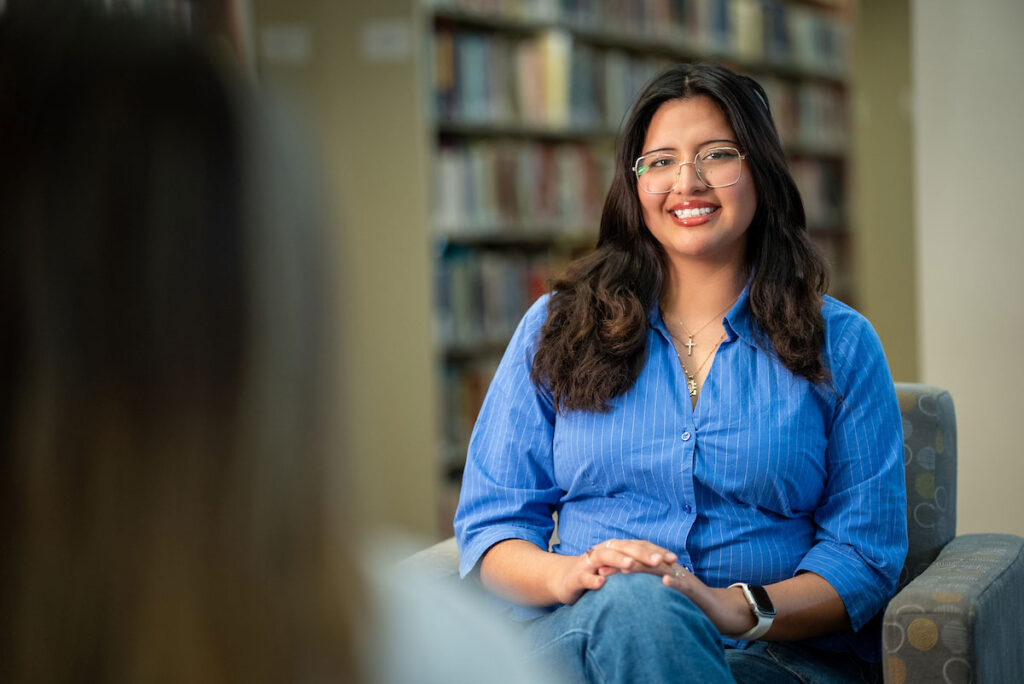 Student sits in a campus library during a conversation.
